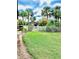 Lush green backyard featuring a fenced in community pool and clubhouse surrounded by tall palm trees at 200 Country Club Dr # 407, Largo, FL 33771
