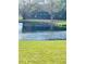 Serene view of a brick building by a pond, framed by lush green grass at 200 Country Club Dr # 407, Largo, FL 33771