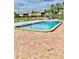 Community pool surrounded by a brick patio and fence with lush landscaping and condo buildings visible in the background at 200 Country Club Dr # 407, Largo, FL 33771