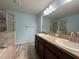 Bathroom featuring double sinks, a framed mirror, and a tiled shower with clear glass door at 20314 Starfinder Way, Tampa, FL 33647