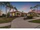 Elegant home featuring a tile roof, lush landscaping, and a circular driveway lined with palm trees at 3830 Moreno Dr, Palm Harbor, FL 34685