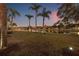 Scenic pond view with lush green lawn, palm trees, and home exterior view in the distance at 3830 Moreno Dr, Palm Harbor, FL 34685