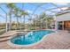 The screened-in pool area features a pool, spa, brick patio, and backyard lake view at 3830 Moreno Dr, Palm Harbor, FL 34685