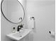 Simple half bathroom with a round mirror, and a small white sink at 4406 W Euclid Ave, Tampa, FL 33629