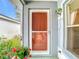 Close-up of a charming front door with a screen and a hanging flower basket at 29523 Waggle Dr, San Antonio, FL 33576