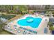 Aerial view of a large community pool with multiple seating areas and well maintained grounds near natural pond and wooded area at 29523 Waggle Dr, San Antonio, FL 33576