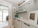 A bar area showcasing white shelving, modern décor, and natural light from a nearby door at 12261 Eldon Dr, Largo, FL 33774