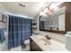 Bathroom with a dark wood vanity, a large framed mirror, a shower with blue curtain, and tile accents at 12261 Eldon Dr, Largo, FL 33774