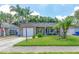Charming single-story home with a well-manicured lawn, palm trees, and inviting front porch at 12261 Eldon Dr, Largo, FL 33774