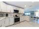 Well-lit kitchen with white cabinetry, stainless steel appliances, marble-look backsplash, and tile floors at 12261 Eldon Dr, Largo, FL 33774