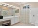 Bright bathroom featuring a glass block shower, a large window, and a long vanity with make up table at 8205 Prairie Ridge Way, Tampa, FL 33647