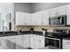 A close-up of the kitchen, featuring stone countertops, stainless steel appliances, and white cabinetry at 8205 Prairie Ridge Way, Tampa, FL 33647