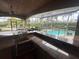 Inviting outdoor kitchen featuring a granite countertop bar overlooking the screened-in pool and patio area at 8503 Kentucky Derby Dr, Odessa, FL 33556