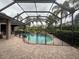 Screened-in pool with safety fence surrounded by lush landscaping and brick patio at 8503 Kentucky Derby Dr, Odessa, FL 33556