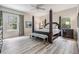 Spacious main bedroom features a four-poster bed, wood flooring, and plenty of natural light from surrounding windows at 19308 Sunset Bay Dr, Land O Lakes, FL 34638