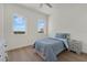 Cozy bedroom with light wood floors, two large windows, a ceiling fan, and a comfortable bed with blue bedding at 2 Aqua Reserve Blvd, New Port Richey, FL 34652