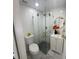 Bathroom featuring a modern glass corner shower, white vanity, round mirror, and grey tile floor at 2540 W Pine St, Tampa, FL 33607