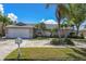 Charming single-story home with a well-manicured lawn, brick driveway, and lush tropical landscaping at 5836 Skimmer Point S Blvd, Gulfport, FL 33707