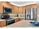 Close-up of a modern kitchen featuring stainless steel appliances, granite countertops, and wood cabinets with tile backsplash at 5836 Skimmer Point S Blvd, Gulfport, FL 33707