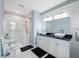 Bathroom featuring a double sink vanity with a glass-enclosed shower and white and black tile floor at 727 Key Royale Dr, Holmes Beach, FL 34217
