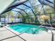 A screened pool with a sun umbrella surrounded by lush landscaping at 8208 Rhanbuoy Rd, Spring Hill, FL 34606