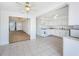 Eat in kitchen features white cabinets and appliances adjacent to a living room with neutral carpet at 10022 Lily N St # N, Pinellas Park, FL 33782