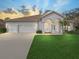 Charming single-story home features a well-manicured lawn, a three-car garage, and a welcoming arched entryway at 1545 Deerbourne Dr, Wesley Chapel, FL 33543