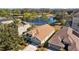Landscaped home overlooks a lake in this aerial view with mature trees in the neighborhood at 18605 Le Dauphine Pl, Lutz, FL 33558