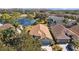 Aerial view of a landscaped home with a lake view, mature trees and neighborhood at 18605 Le Dauphine Pl, Lutz, FL 33558