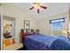 Bright bedroom featuring a plush bed with blue quilt, ceiling fan, and large window at 18605 Le Dauphine Pl, Lutz, FL 33558