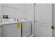 Well-lit laundry room features a washer, dryer, shelving and a door to the left at 18605 Le Dauphine Pl, Lutz, FL 33558