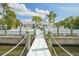 Waterfront home featuring a private dock with lush tropical landscaping and spacious deck with ample seating at 6446 Lake Sunrise Dr, Apollo Beach, FL 33572