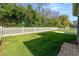 Lush green backyard with manicured lawn, bordered by mature trees and a white picket fence at 4446 Wildstar Cir, Wesley Chapel, FL 33544