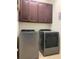 Laundry room with modern washer, dryer, and dark wood upper cabinets at 4446 Wildstar Cir, Wesley Chapel, FL 33544