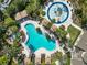 Aerial view of a uniquely shaped pool, splash pad, lounge chairs, and lush landscaping at 4446 Wildstar Cir, Wesley Chapel, FL 33544