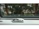 Close-up of a window with PCT lock, offering a view of lush greenery and palm trees at 1216 S Missouri Ave # 224, Clearwater, FL 33756