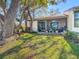 The backyard features a screened patio and green grass, shaded by mature trees offering a serene outdoor space at 2606 Oak Cir, Tarpon Springs, FL 34689