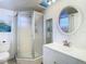 Bright bathroom featuring a corner shower with glass doors and a modern vanity with round mirror at 2606 Oak Cir, Tarpon Springs, FL 34689