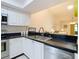 Well-lit kitchen featuring white cabinetry, black countertops and stainless steel appliances, blending style with functionality at 2606 Oak Cir, Tarpon Springs, FL 34689
