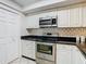 Kitchen featuring stainless steel appliances, white cabinets, and a modern backsplash for a sleek and functional space at 2606 Oak Cir, Tarpon Springs, FL 34689
