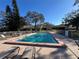 Community pool with brick paver deck, lounge chairs, and tables, surrounded by lush trees at 2606 Oak Cir, Tarpon Springs, FL 34689
