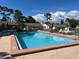 Community pool with chairs and tables around the perimeter for outdoor relaxation at 2606 Oak Cir, Tarpon Springs, FL 34689