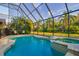 Outdoor pool with attached spa, screened-in enclosure, and a view of lush greenery at 10534 Bermuda Isle Dr, Tampa, FL 33647
