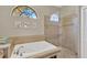 Relaxing bathroom with tub, shower, and a curved transom window at 11209 Bloomington Dr, Tampa, FL 33635