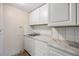 Galley kitchen with white cabinets, a stainless steel sink, and a faux marble countertop at 1157 Brook Rd, Clearwater, FL 33755