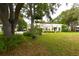 Inviting home exterior with a lush green front yard and mature trees, showcasing curb appeal at 1372 Palmetto St, Clearwater, FL 33755