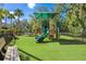 Community playground area with a slide, climbing structures, and benches, all set on a safety-first synthetic grass surface at 16331 Burniston Dr, Tampa, FL 33647