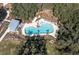 Aerial view of a community pool with sun loungers and a covered area surrounded by trees at 4132 Woods Rider Loop, Odessa, FL 33556