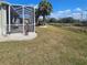Large backyard featuring green lawn, a screened patio, and tropical palm trees against a beautiful blue sky at 920 Regal Manor Way, Sun City Center, FL 33573
