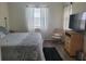 Bedroom with queen-sized bed, side table, and wicker TV stand, complemented by natural light from the large window at 920 Regal Manor Way, Sun City Center, FL 33573